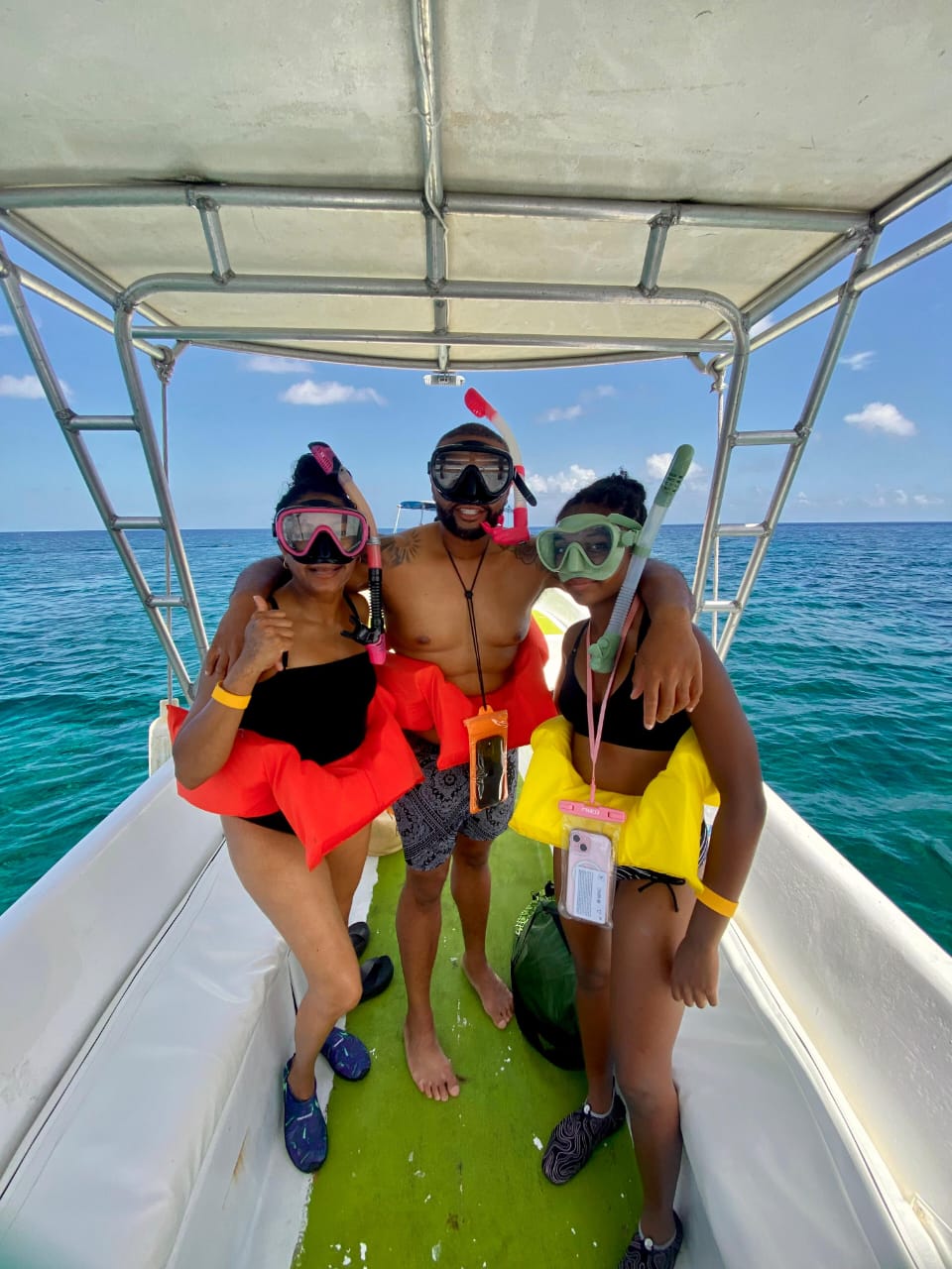Three guests with snorkel masks and life vests on a Roatán boat