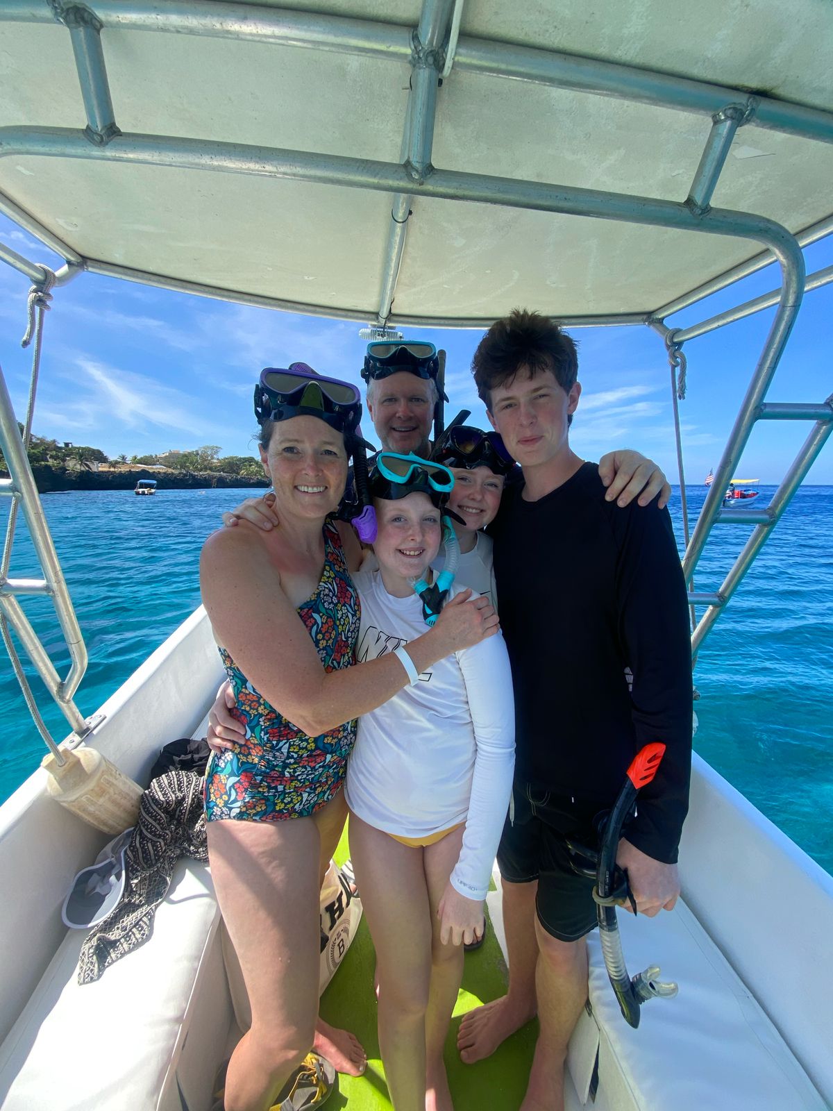 Family with snorkel gear on a boat in Roatán's turquoise water